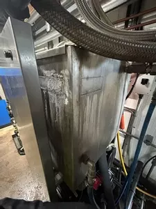 Original leaking water tank on Nilfisk Delta Booster multi-pump pressure washer system before replacement.